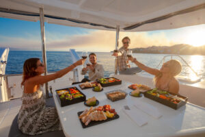 Grupo de amigos disfrutando de aperitivos y bebidas al atardecer en un catamarán durante el tour Luxury Sunset de Vallarta Adventures en la Bahía de Banderas